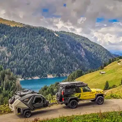 Kompakter EdgeOut Teardrop-Camper wird von einem gelben Geländewagen auf einer Bergstraße gezogen