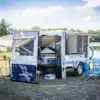 Farfalla Camper flap aufgefaltet mit Vorzelt und Campingausstattung am Seeufer