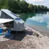 Farfalla Camper flip mit geöffnetem Aufstelldach und Markise an einem Seeufer