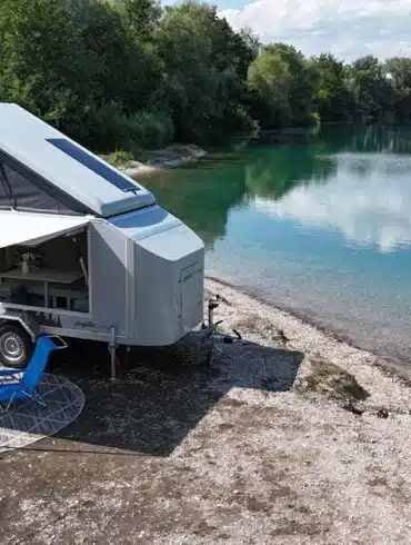 Farfalla Camper flip mit geöffnetem Aufstelldach und Markise an einem Seeufer