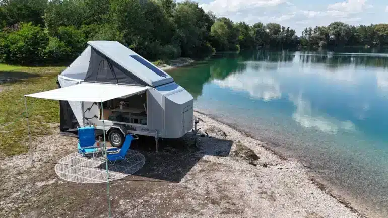 Farfalla Camper flip mit geöffnetem Aufstelldach und Markise an einem Seeufer