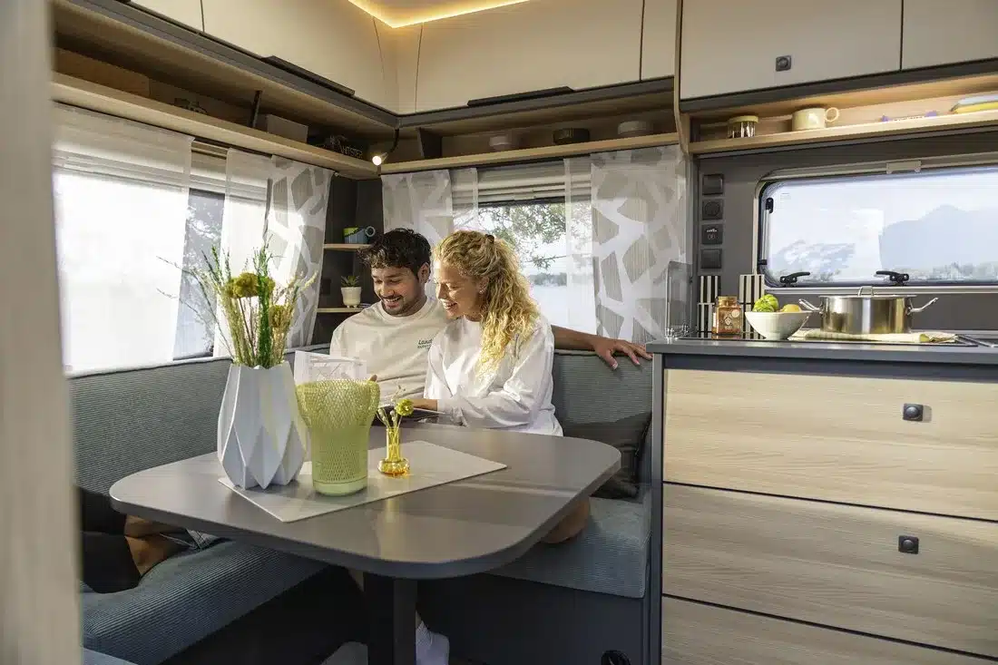 Innenraum eines Fendt-Caravan APERO mit Sitzgruppe, Küche, Oberschränken und moderner Beleuchtung
