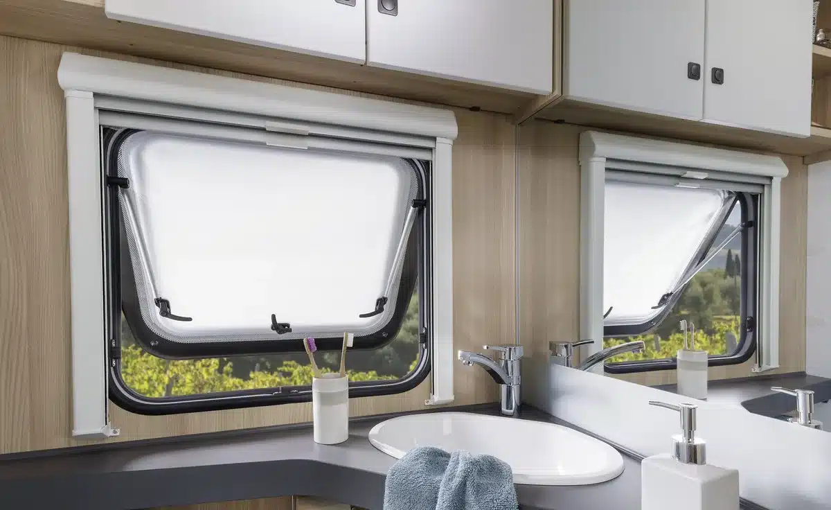 Innenansicht des hellen Badbereichs im Fendt-Caravan APERO mit Waschbecken, Armaturen, Spiegel und Fenstern