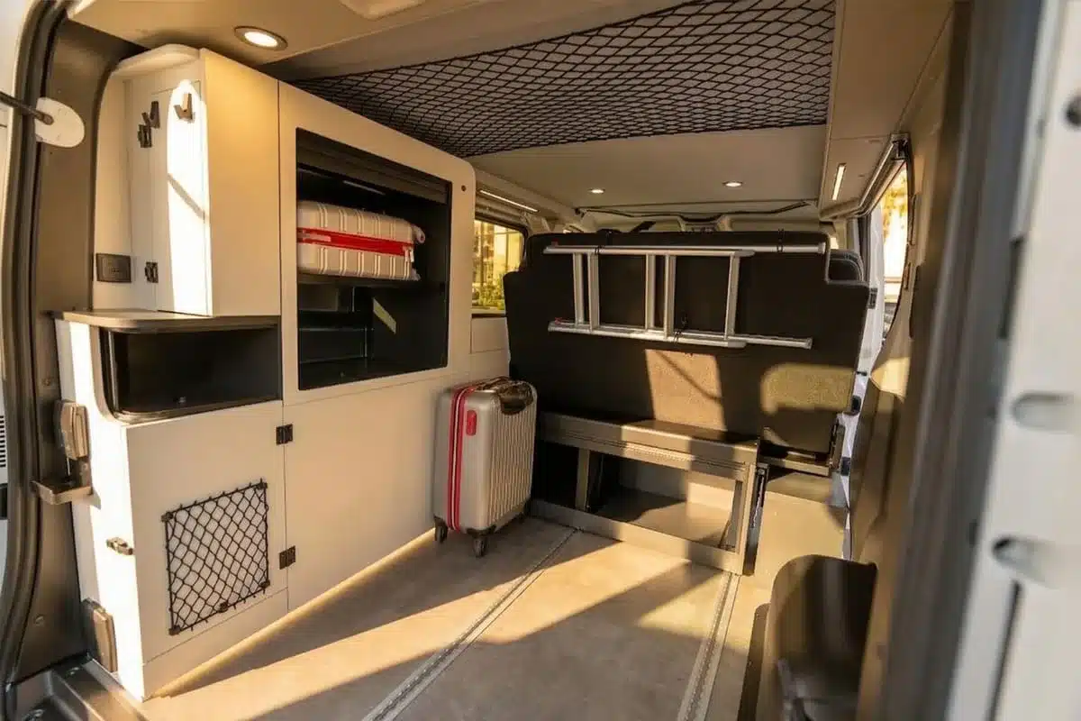 Innenraum des Flex 5 Campervans mit Koffer, Stauraum, Sitzbank und Einbauküche.