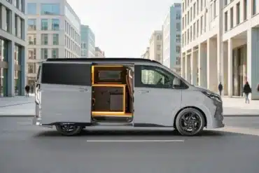 Grauer Ford Custom Flex von Wavecamper mit geöffneter Schiebetür und integrierter Campingküche in einer Stadtstraße