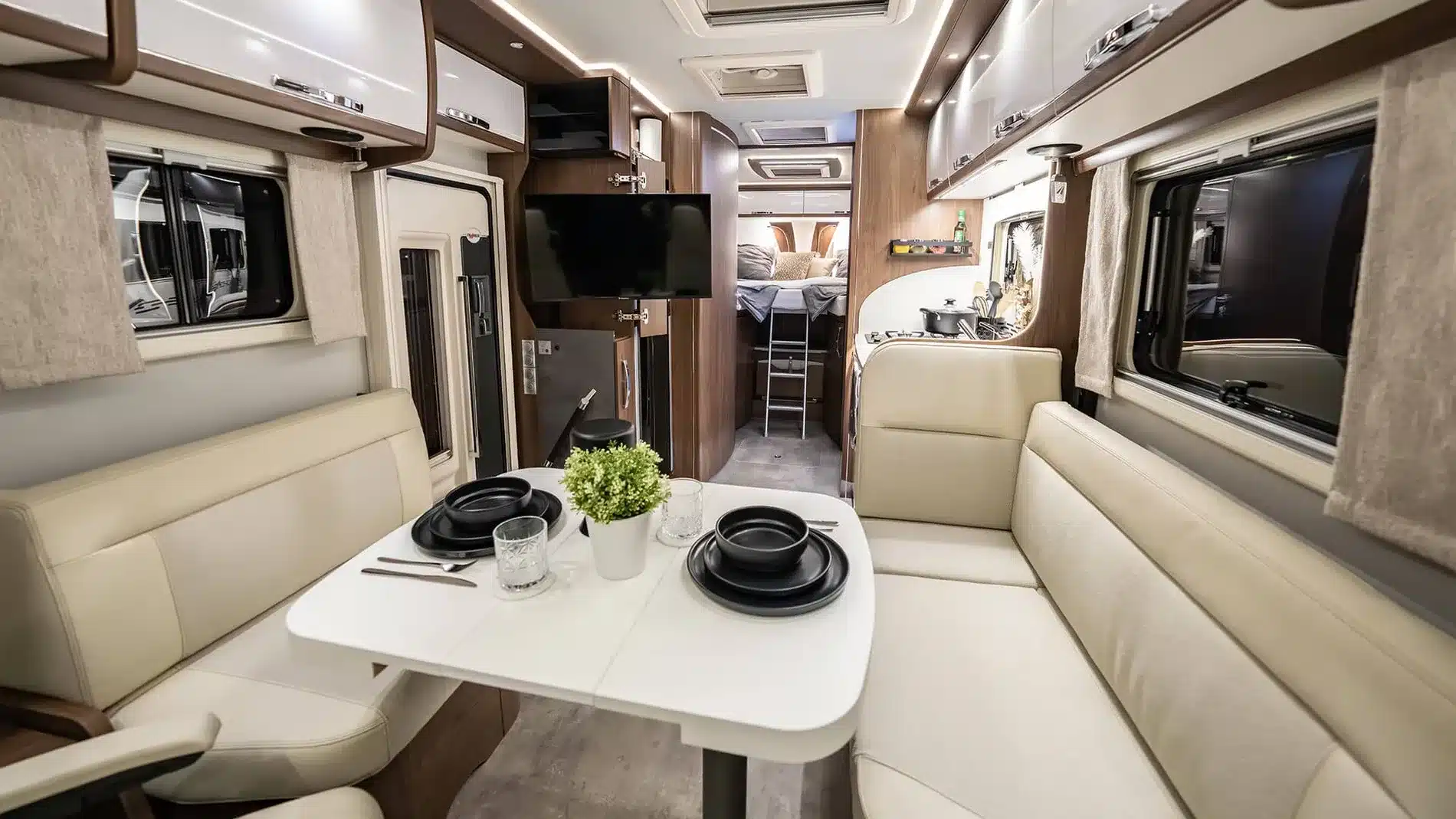 Heller Innenraum eines FRANKIA Reisemobils mit Sitzgruppe, Esstisch, Küche und Schlafbereich