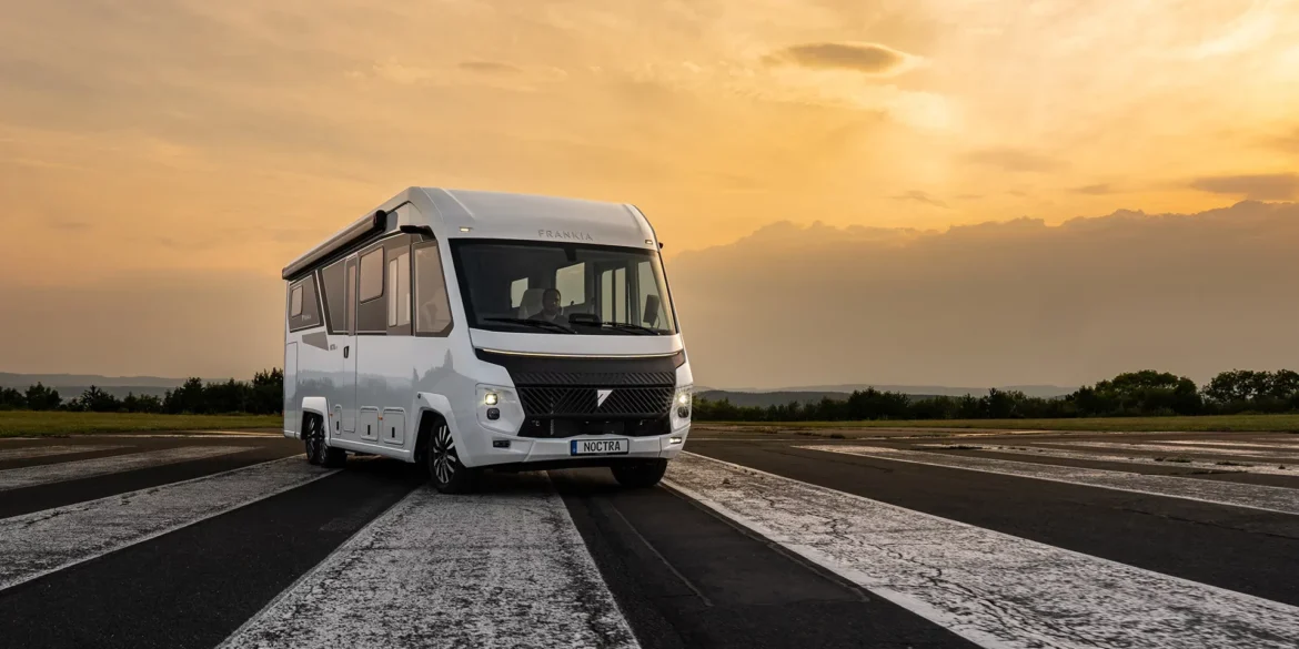 Weißer FRANKIA NOCTRA Liner als integriertes Luxuswohnmobil auf einer Fahrbahn bei Sonnenuntergang
