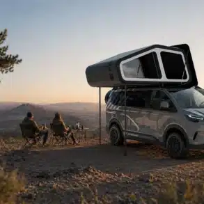 Freescape Adventure Line Campervan mit ausgefahrenem Schlafdachzelt und zwei Personen beim Outdoor-Camping vor Panorama-Landschaft.