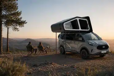 Freescape Adventure Line Campervan mit ausgefahrenem Schlafdachzelt und zwei Personen beim Outdoor-Camping vor Panorama-Landschaft.