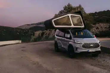 Der Freescape Street Line Campervan mit aufgeklapptem, aufblasbarem Dachzelt steht auf einer Straße in Gebirgslandschaft.