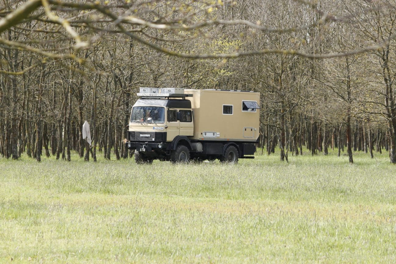 Expeditionsmobil beim Freistehen auf einer Wiese zwischen Bäumen in Ungarn