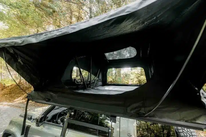 Geöffnetes Go Overland Voyage Hybrid-Dachzelt auf einem Fahrzeug mit Fenstern, Leiter und schwarzem Zelttuch