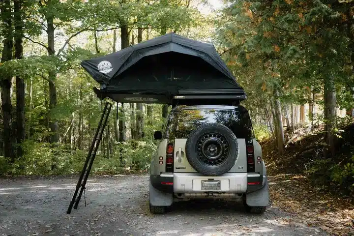 Geöffnetes Go Overland Voyage Hybrid-Dachzelt auf einem SUV mit Leiter im Wald