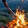 Donkey Tong Grillzange hält Holz über offenem Lagerfeuer im Outdoor-Einsatz