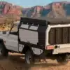 Pick-up mit montiertem i-p2 Camper-Modul von Feniks Campers auf einer staubigen Geländepiste im Süden Afrikas, typische Offroad-Szenerie.
