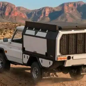 Pick-up mit montiertem i-p2 Camper-Modul von Feniks Campers auf einer staubigen Geländepiste im Süden Afrikas, typische Offroad-Szenerie.