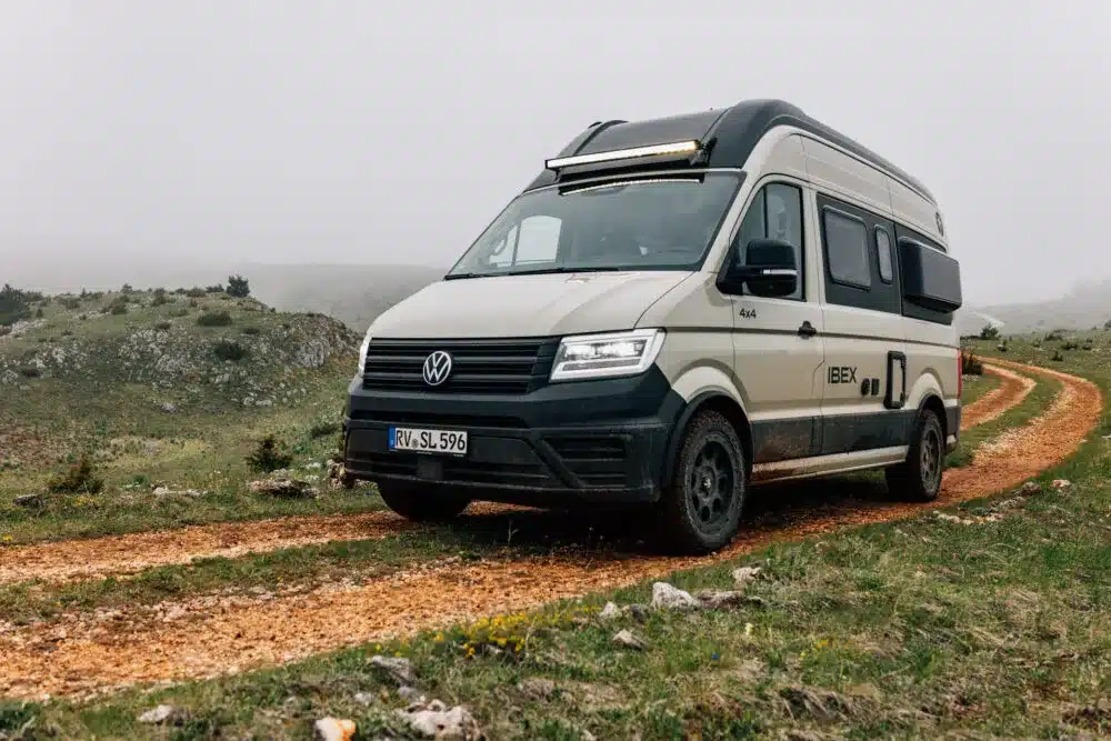 VW Crafter Sunlight IBEX 4x4 Campervan auf Schotterpiste in bergiger Landschaft.