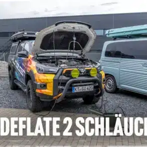 InDeflate Reifendrucksystem im Einsatz: Zwei Schläuche verbinden einen Offroad-Camper mit dem Kompressor, Hintergrund Vans und Campingfahrzeuge.