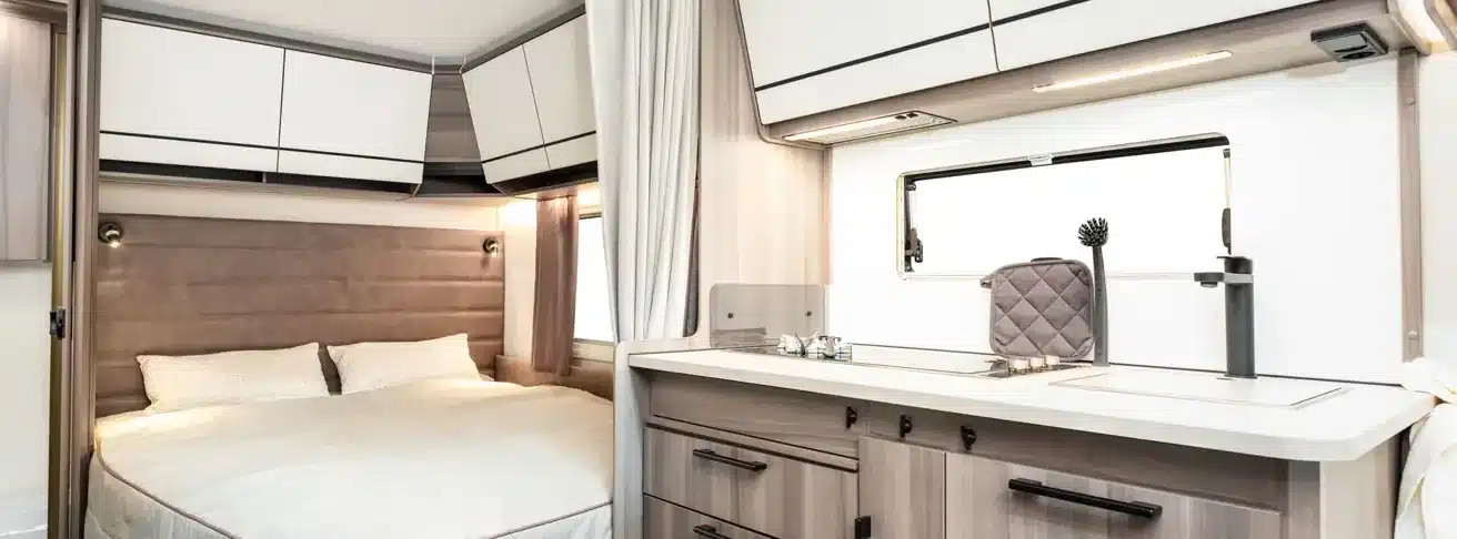 Innenraum des KABE Estate 470 XL mit Doppelbett, Küchenzeile, Spüle, Armatur und Oberschränken
