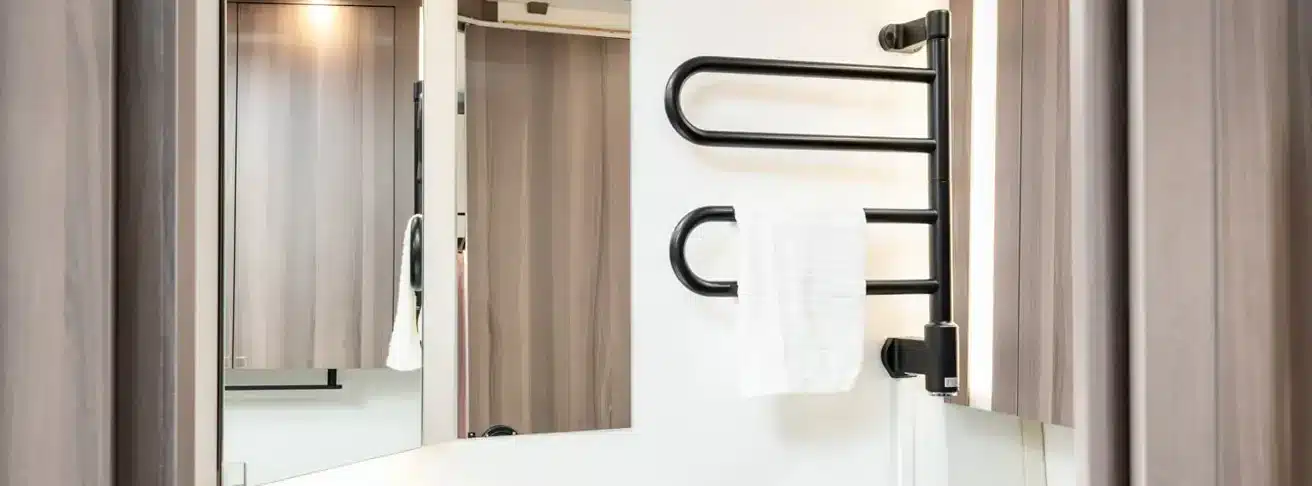 Badezimmer im KABE Estate 470 XL mit schwarzem Handtuchheizkörper, Spiegel und Holzschränken