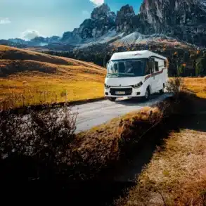 Weißes vollintegriertes Malibu Wohnmobil auf einer Bergstraße vor einer alpinen Felslandschaft