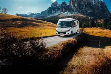 Weißes vollintegriertes Malibu Wohnmobil auf einer Bergstraße vor einer alpinen Felslandschaft