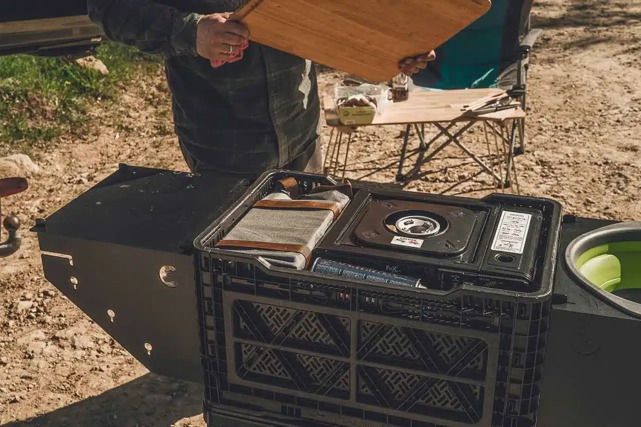 Nakatanenga Küchenkiste 2.0 geöffnet mit integriertem Gaskocher und Campingzubehör beim Camping im Freien.