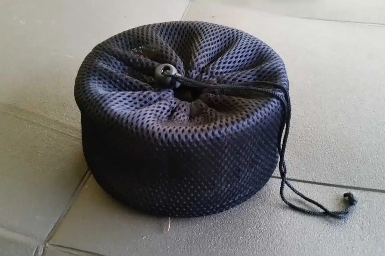 Schwarzer Netzbeutel mit Kordelzug auf einem hellen Boden
