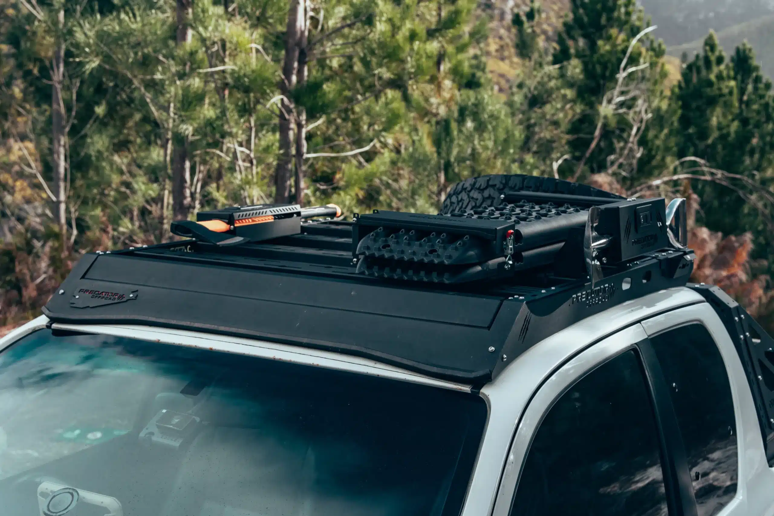 Predator Offroad Stealth Dachplattform mit montiertem Zubehör auf einem weißen Jeep Wrangler JK, Wald im Hintergrund