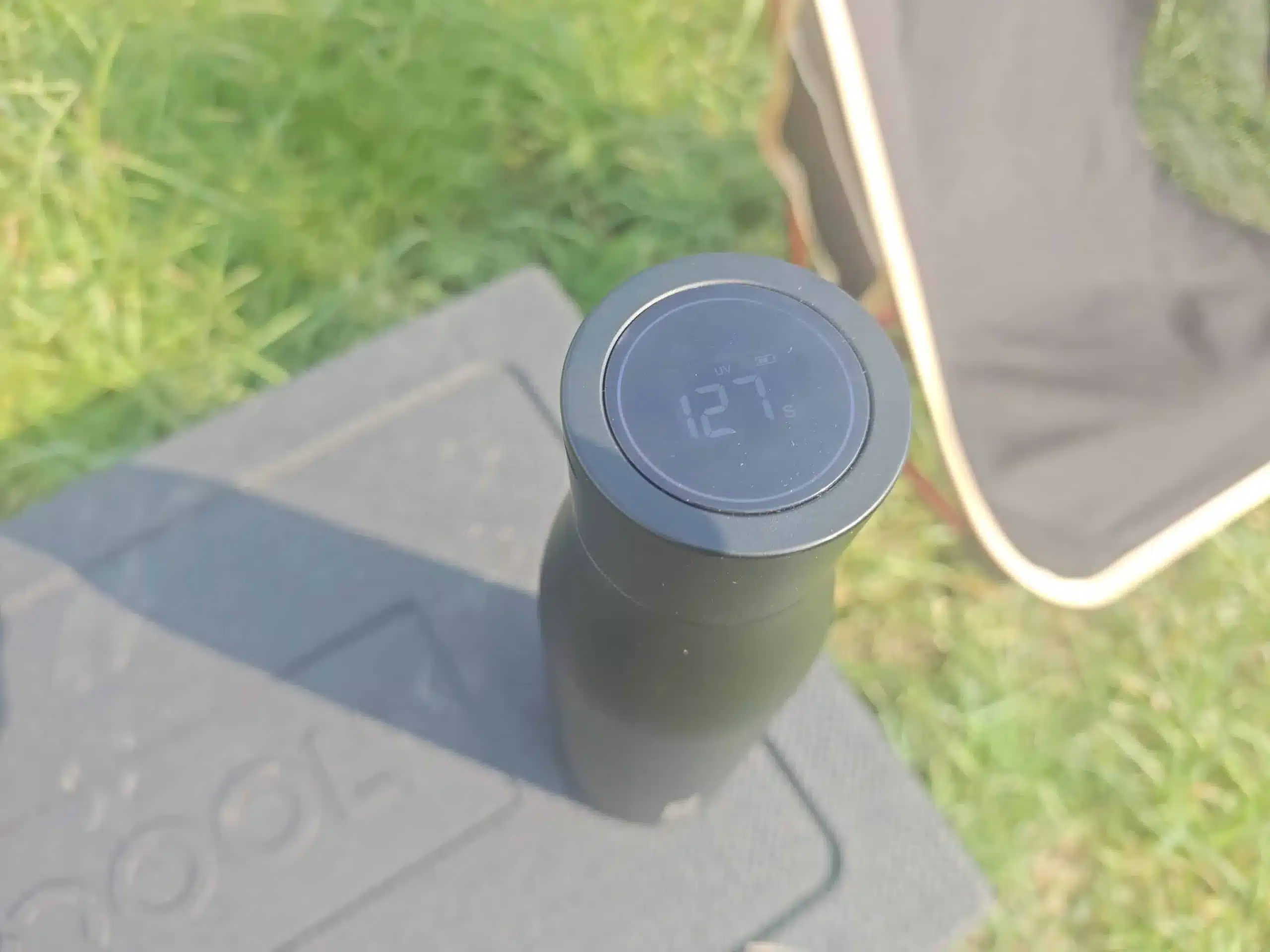 Schwarze QOOL Bottle mit digitaler Temperaturanzeige auf einem Tisch im Freien