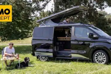 Schwarzer Reimo Van-Concept Campervan mit geöffnetem Aufstelldach auf einer Wiese