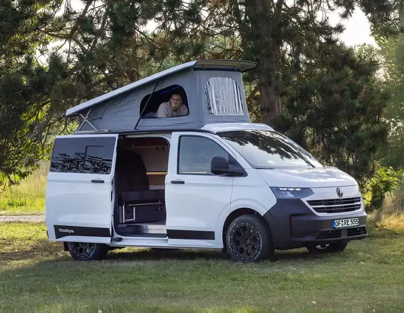 Weißer Campervan des Reimo Van Concept mit Aufstelldach und geöffneter Schiebetür
