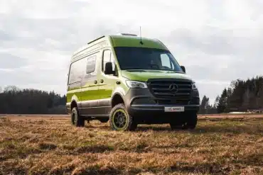 Grüner Rhön Camp The Spirit auf Mercedes-Sprinter-Basis steht auf einer Wiese vor einem Wald