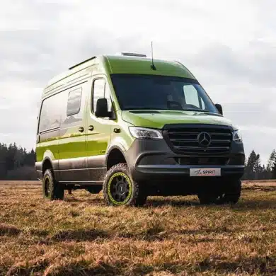 Grüner Rhön Camp The Spirit auf Mercedes-Sprinter-Basis steht auf einer Wiese vor einem Wald