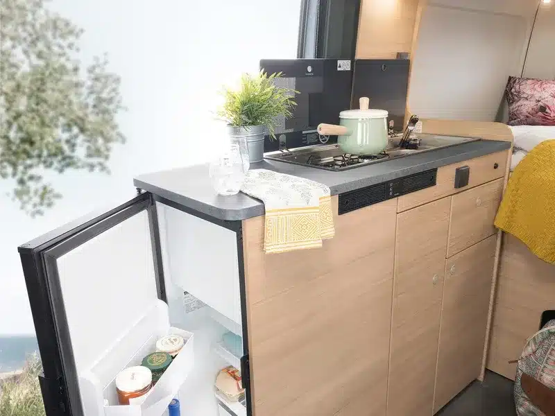 Innenraum des ROADCAR R540 mit Küchenzeile, geöffnetem Kühlschrank und Schlafbereich