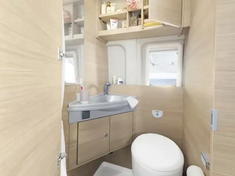 Innenansicht eines Campervan-Bads mit Waschbecken, Toilette und Stauraum