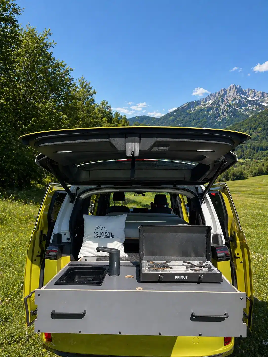 Campingbox S KISTL Star mit aufgebauter Küche im geöffneten Kofferraum eines Vans in der Natur.