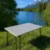 Stabiler, minimalistischer Campingtisch aus Birke Multiplex mit Metallbeinen am Seeufer, im Grünen, vor Alpenpanorama