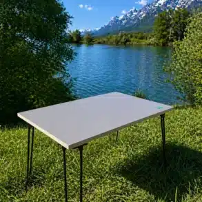 Stabiler, minimalistischer Campingtisch aus Birke Multiplex mit Metallbeinen am Seeufer, im Grünen, vor Alpenpanorama