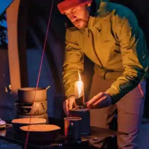 Person zündet die Snowdon Gaslaterne auf einem Campingtisch an einem Zelt an