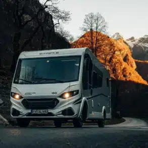 Weißes Sunlight I 68 Adventure Reisemobil auf einer Bergstraße vor herbstlicher Alpenkulisse