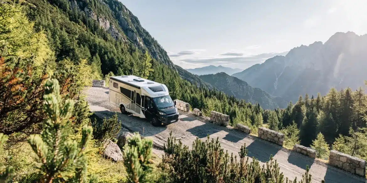Sunlight Teilintegriertes Adventure Reisemobil auf einer kurvenreichen Bergstraße vor einer alpinen Landschaft