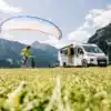 Weißer Sunlight VANS Adventure auf einer Wiese vor den Bergen mit Gleitschirm und Familie
