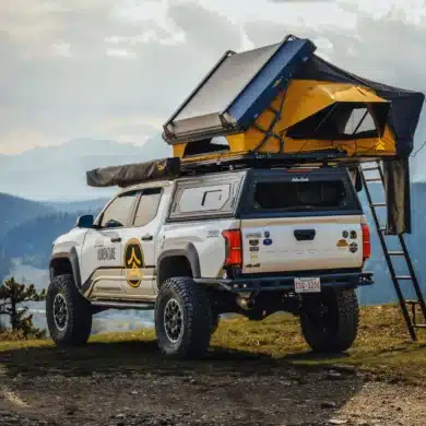 Ein geöffnetes Dachzelt The Cabin 2.0 XL auf einem weißen Pickup-Truck mit Leiter, aufgebaut am Rand eines Bergplateaus.