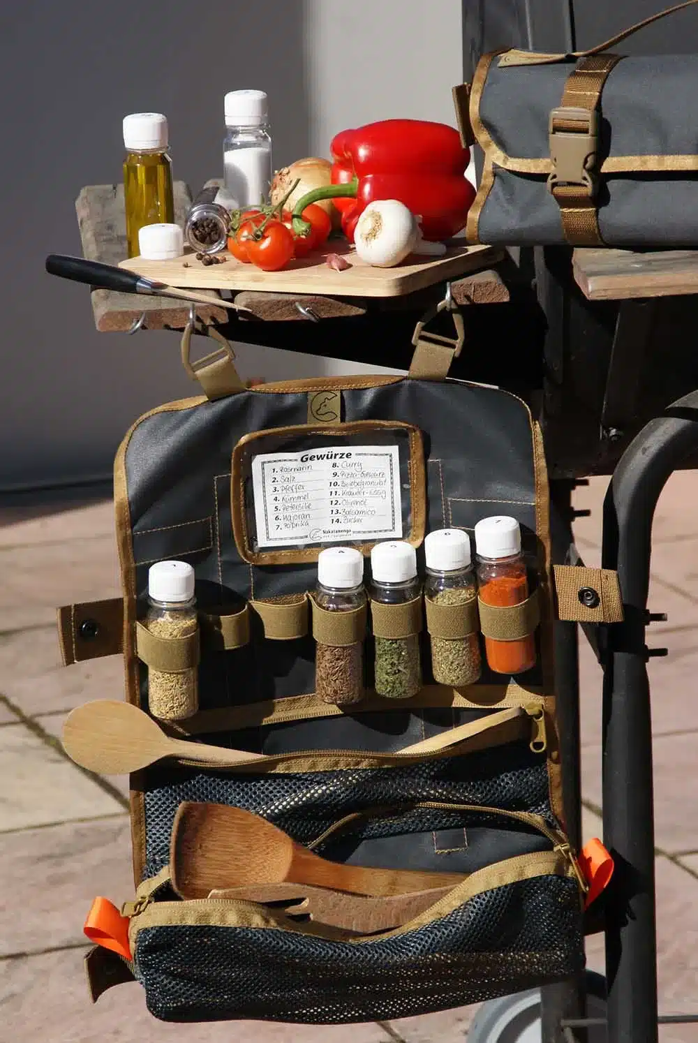 Detailaufnahme der Tool Roll Spice 2 mit sieben Gewürzbehältern, Mesh-Tasche und Kochzubehör beim Outdooreinsatz.