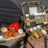 Ausgerollte Tool Roll Spice Gewürztasche mit befüllten Behältern, daneben frisches Gemüse auf einem Brett