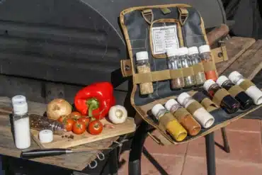 Ausgerollte Tool Roll Spice Gewürztasche mit befüllten Behältern, daneben frisches Gemüse auf einem Brett