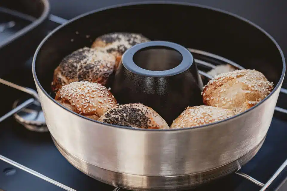 Mobiler Backofen mit mehreren belegten Aufbackbrötchen auf einem Kochfeld