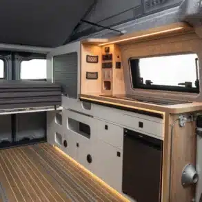 VW Caravelle Flex Innenraum mit moderner Küchenzeile, Stauraum und Faltdach.