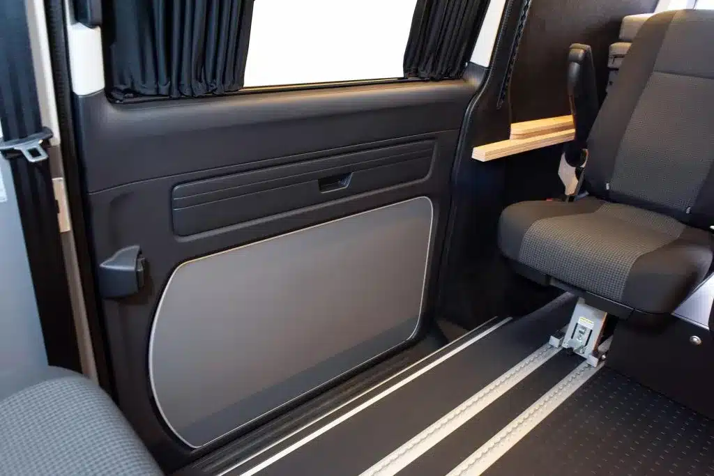 Innenraum des VW Transporter Flex E-Line mit Einzelsitz, Sitzschienen und seitlicher Schiebetür